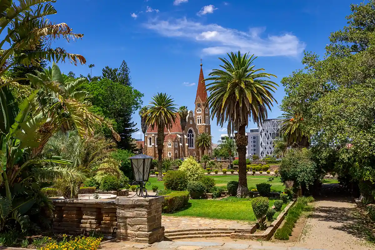 Windhoek's Christuskirche viewed across the Tintenpalast Gardens with palm trees in the foreground.